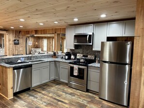 A modern kitchen with wooden paneling, stainless steel appliances, and a granite countertop.