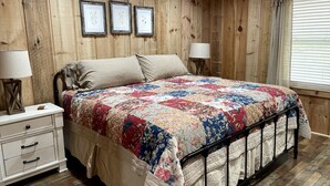 Ein Schlafzimmer mit Holzwandpaneelen, einem Bett, Nachttischen und gerahmten Bildern an der Wand.