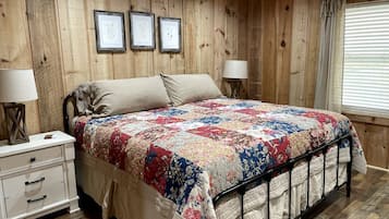 A wooden-paneled bedroom with a bed, bedside tables, and framed pictures on the wall.
