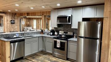 A modern kitchen with wooden paneling, stainless steel appliances, and a granite countertop.