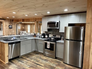 A modern kitchen with wooden paneling, stainless steel appliances, and a granite countertop.