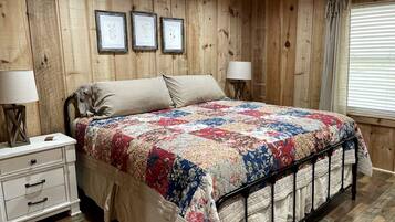 A wooden-paneled bedroom with a bed, bedside tables, and framed pictures on the wall.