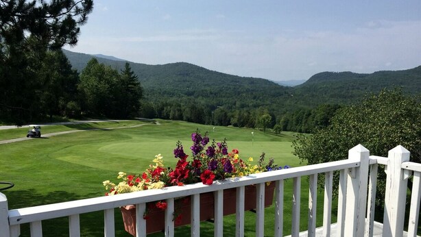 A view of a golf course with a white fence and flower boxes in the foreground.