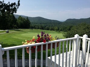 Vista de um campo de golfe com uma cerca branca e floreiras em primeiro plano.