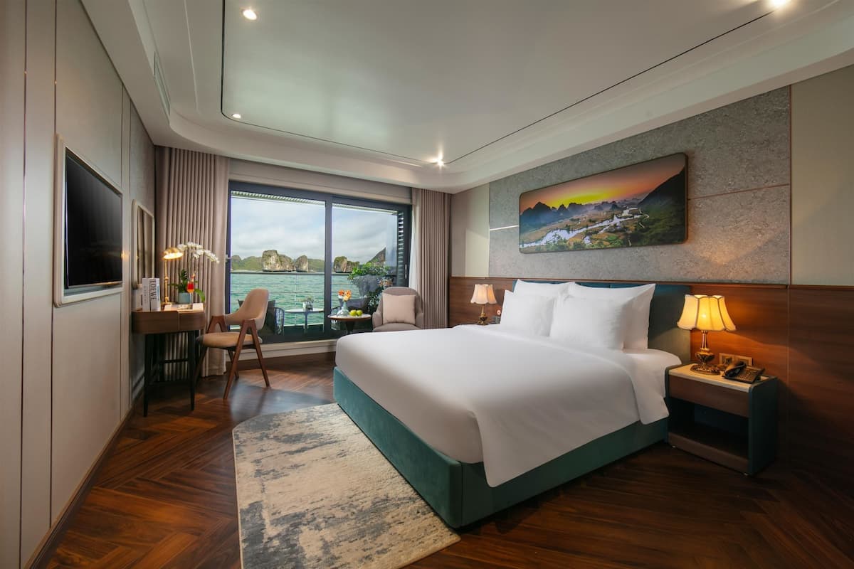 Ein Hotelzimmer mit einem großen Bett, einem Schreibtisch mit Stuhl, einem Fernseher und einem Fenster mit Meerblick.