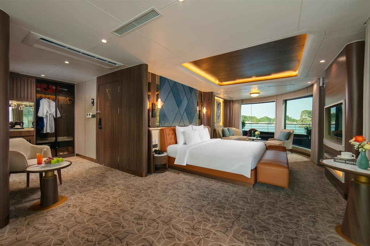 Ein modernes Hotelzimmer mit einem großen Bett, einer Sitzecke, einem Schminktisch und Blick ins Freie.