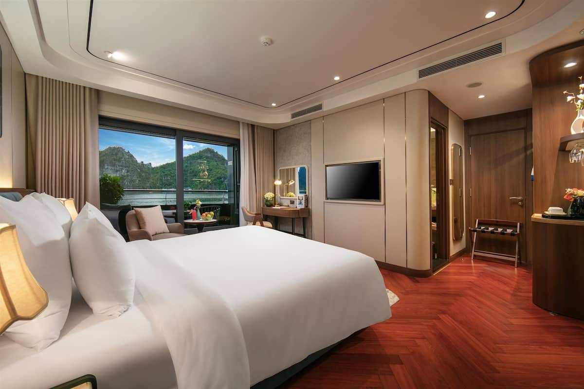 Ein modernes Hotelzimmer mit einem großen Bett, einem Fernseher, einem Schreibtisch und Blick ins Freie.