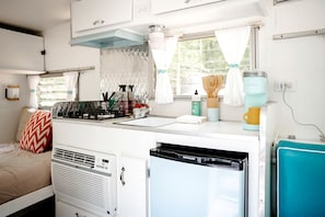 A compact kitchenette with a stove, sink, and a small refrigerator.