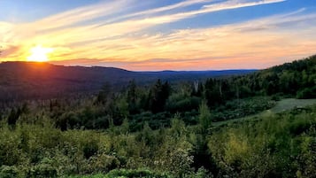 A natural landscape with a sunset, hills, and a path.