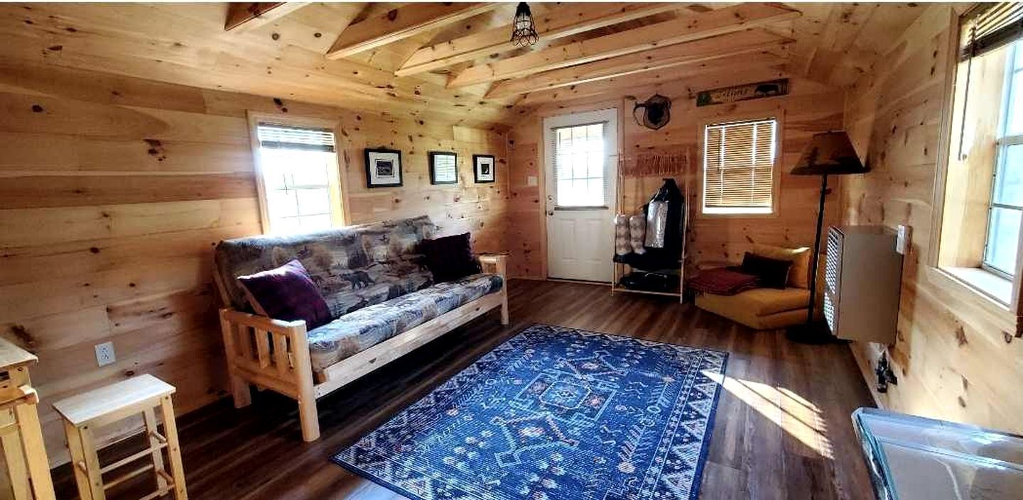 L’intérieur d’un chalet en bois, avec un canapé, un tapis, une lampe et un téléviseur.