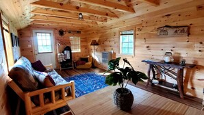 Ein Holzblockhaus-Interieur mit einer Couch, einem Tisch, einer Pflanze und einem Fenster.