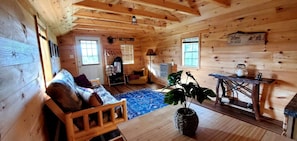 Ein Holzblockhaus-Interieur mit einer Couch, einem Tisch, einer Pflanze und einem Fenster.