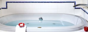 Una bañera con una llave, un objeto rojo al lado y una pared con azulejos azules.