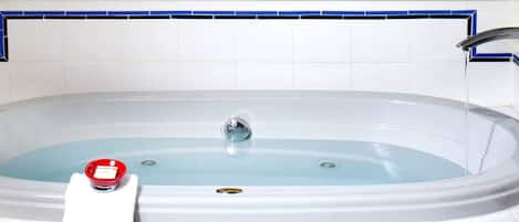 A bathtub with a faucet, a red object on the side, and a blue-tiled wall.