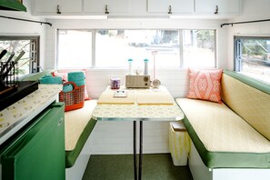 Une petite cuisine équipée comprenant une table, une radio et une fenêtre donnant sur l’extérieur.