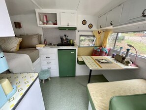 A compact kitchenette with a sink, stove, and storage cabinets. There is a small dining table and a bench.