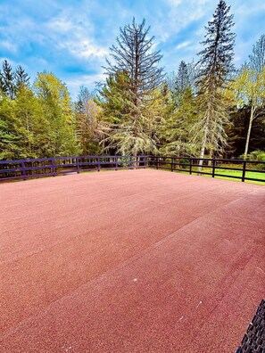 Ein roter Sportplatz mit umgebendem Zaun und Bäumen.