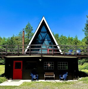 A cabin with a red door, a wooden deck, and two blue chairs. - Spacious Well Furnished A-Frame with Sauna in Union Dale, Pennsylvania (Union Dale)