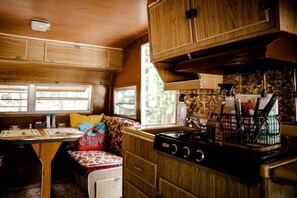 A compact RV kitchen with a stove, sink, and wooden cabinets.