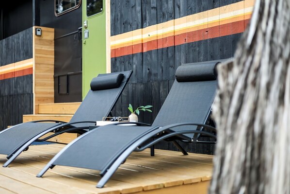 Three sun loungers with a small plant and a wooden table.