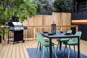 An outdoor patio with a grill, a table, and green chairs.