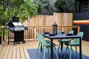An outdoor patio with a grill, a table, and green chairs.