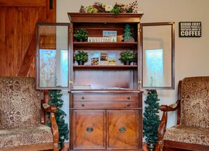 A wooden cabinet with a 'WELCOME' sign, a Christmas tree, and a framed mirror.
