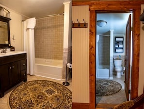A bathroom with a bathtub, toilet, and a wooden door.