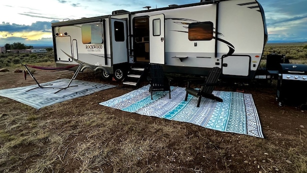 Een camper met een keukenhoek, een eettafel en een barbecue.