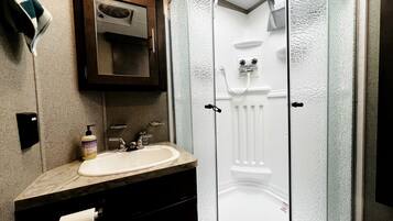 A bathroom with a sink, mirror, and glass shower enclosure.