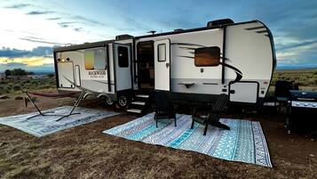 A recreational vehicle with a kitchen area, a dining table, and a grill.