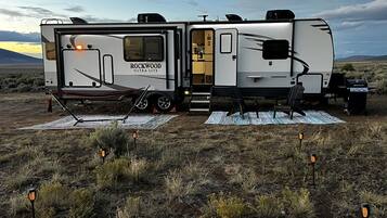 Una caravana Rockwood Ultra Lite estacionada en un campo bajo un cielo despejado.