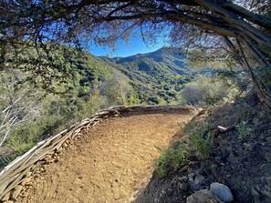 A dirt path with a wooden fence, surrounded by trees and hills. - Charming Cabin Ideal for Hikers and Nature Lovers in Topanga, California (Topanga)