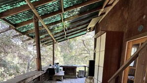 A rustic wooden structure with a covered outdoor area, a dining table with woven placemats, and a stone fireplace.