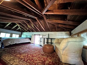 Una habitación con una cama, un sofá, un pequeño reposapiés, una ventana y una tradicional pantalla japonesa shoji.