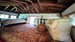 A room with a bed, a sofa, a small ottoman, a window, and a traditional Japanese shoji screen.