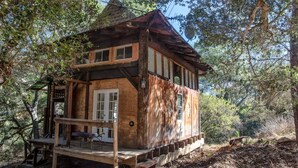 Una cabaña rústica con terraza de madera, ventanas amplias y una chimenea.