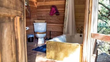 Een houten badkamer met een toilet, een wastafel en een bad.