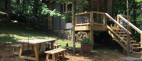 Una cabaña de madera con un porche y escaleras, rodeada de árboles.