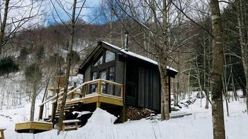 A cabin with a wooden deck and a staircase leading to the entrance.