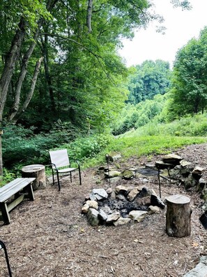Ein Campingplatz mit Feuerstelle, Holzbanken und einem Stuhl.