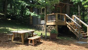 A wooden cabin with a deck and stairs, surrounded by trees.