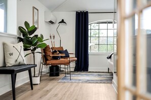 Una sala de estar moderna con un sofá de cuero, una mesa de centro, una planta en maceta y un amplio ventanal con cortinas.