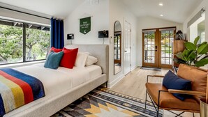 Un dormitorio moderno con una cama grande, un ventilador de techo, vistas al exterior y un letrero verde en la pared.