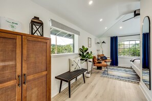 A modern living room with a wooden cabinet, a bench, a potted plant, a sofa, and a large window with curtains. - Outstanding Modern Cabin with Spectacular Outdoor and Indoor Areas in Texas (Leander)
