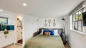 Ein Schlafzimmer mit Bett, Fenster, Fernseher und einer Küchenzeile.