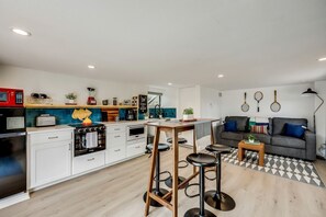 A modern kitchen with white cabinets, a red microwave, and a black refrigerator.