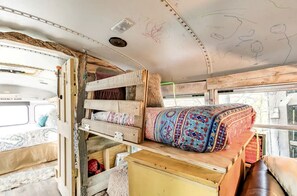 A compact RV interior with a bunk bed, a small table, and a window. - Cozy Hot Tub “Love Bus” near Augusta, Kentucky (Germantown)