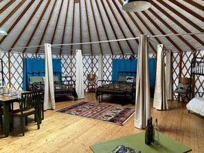 A yurt with two beds, a dining area, and a wooden floor.