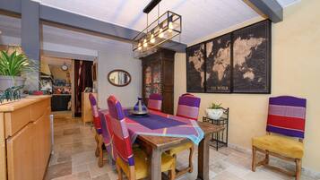 A dining area with a wooden table, chairs, a world map on the wall, and a hanging light fixture.